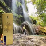 A man standing in front of a waterfall next to a phone.