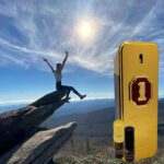 A person on top of a rock with an iphone.