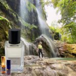 A person standing in front of a waterfall with a bottle.