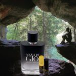 A bottle of perfume and a roll of parfum sitting in front of a cave.