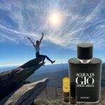 A person is sitting on top of a rock with an acqua di gio perfume.