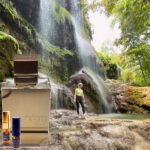 A person standing in front of a waterfall.