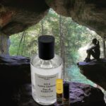 A bottle of lotion and a vial sitting in front of a cave.