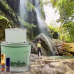 A person standing in front of a waterfall with a bottle.