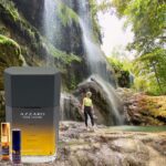 A man standing in front of a waterfall next to some water.