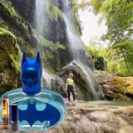 A batman bottle and some water in front of a waterfall.