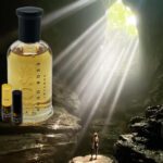 A bottle of perfume and some oils in front of a cave.