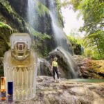 A person standing in front of a waterfall with a bottle.