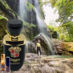 A man standing in front of a waterfall next to a bottle.