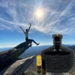 A person jumping in the air over a rock with a bottle of perfume.