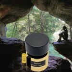 A jar of face cream and a bottle of oil in front of a cave.