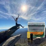 A person on top of a rock with a beer.