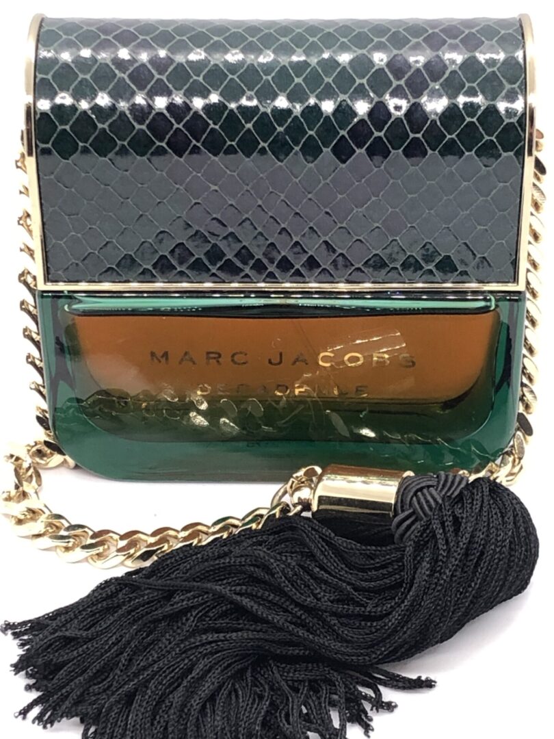 A green purse with a black tassel on top of it.