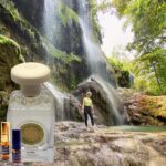 A person standing in front of a waterfall with bottles.