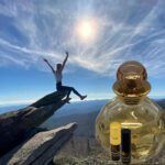 A person on top of a mountain with an open bottle.