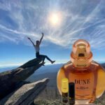 A person is jumping over rocks with dune perfume.