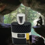 A bottle of perfume sitting in front of a cave.