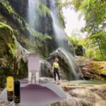 A person standing in front of a waterfall.