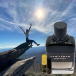 A man is jumping over the rocks with a bottle of perfume.