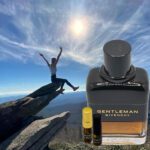 A man is jumping over the rocks with a bottle of perfume.