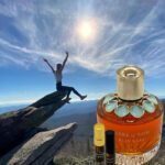 A person is sitting on the top of a mountain with an orange bottle.