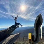 A person on top of a rock with a surfboard.