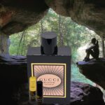 A bottle of gucci perfume sitting in front of some rocks.