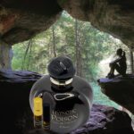 A bottle of perfume sitting in front of a cave.