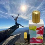 A person is jumping off of a cliff with a bottle and two oils.