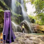 A person standing in front of a waterfall.