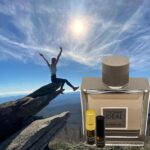 A man is jumping over rocks with a bottle of perfume.