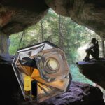 A person sitting in the cave with an umbrella.