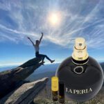 A person is standing on top of a mountain with a bottle.