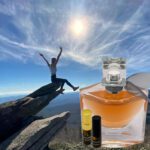 A person jumping in the air next to an open bottle of perfume.