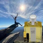 A person jumping in the air next to an open bottle of perfume.