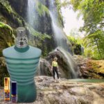 A bottle of perfume and a person in front of a waterfall.