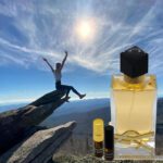 A person jumping in the air next to a bottle of perfume.