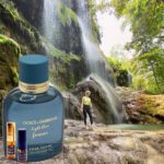 A man standing in front of a waterfall next to a bottle.