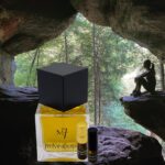 A bottle of perfume sitting in front of a cave.