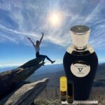 A person jumping in the air over rocks with a bottle of perfume.