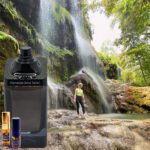 A person standing in front of a waterfall next to some water.