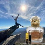 A person jumping over rocks with a bottle of perfume.