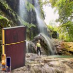 A person standing in front of a waterfall.