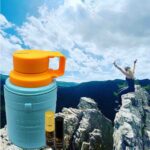 A person on top of a mountain with a thermos.