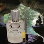 A bottle of perfume sitting in front of a cave.