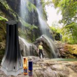 A person standing in front of a waterfall next to a tube.