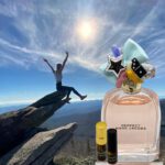 A person jumping in the air over a cliff with a bottle of perfume.