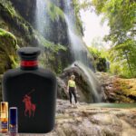 A man standing in front of a waterfall next to a bottle.