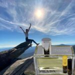 A person is sitting on top of a rock with a bottle.