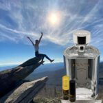 A person jumping in the air next to a bottle of perfume.